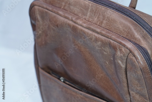 Close-up of a stylish, distressed brown leather bag featuring a prominent zipper and front pocket detail.