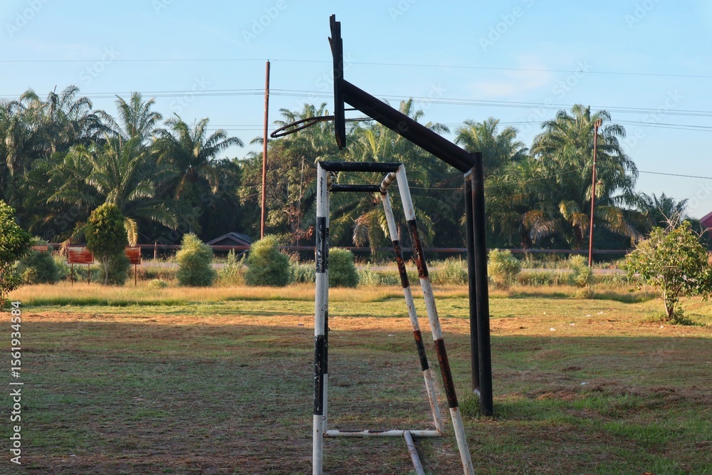 Fototapeta premium Outdoor sports field with basketball hoop and smaller goal in tropical setting under clear sky