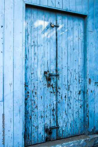 Locked and bolted old blue wooden door with paint peeling off