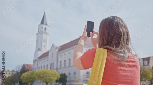 Woman taking photo of historic building with smartphone