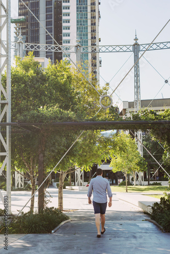 Man walking under a large structure in a city urban park