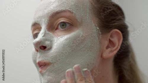 Woman applying green facial mask