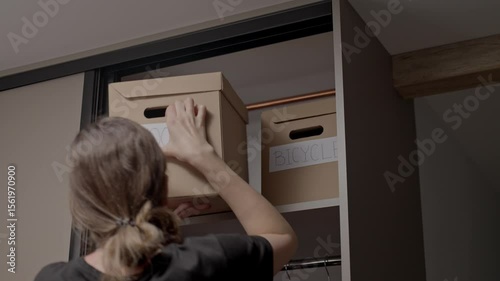 Woman organizing labeled boxes in wardrobe shelf