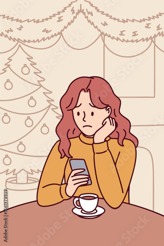 Young woman sits alone indoors during Christmas night holding hot drink and feeling sad and lonely