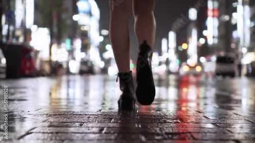A cinematic close-up of a person walking in high heels on a wet city street, reflecting neon lights during nighttime, creating a moody urban atmosphere.