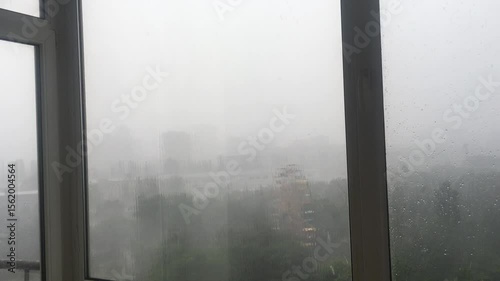 Heavy rain behind the window. Heavy raindrops hitting the glass, low visibility, monsoon season.