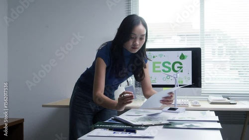 Professional female financial analyst reviewing sustainability strategy documentation, evaluating environmental and corporate governance data at modern workspace