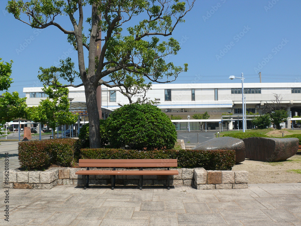 Fototapeta premium A bench installed in the small garden in front of the local train station.