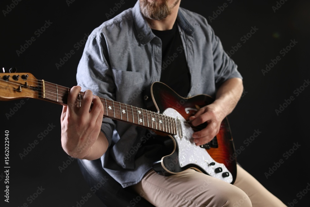 Obraz premium Man playing guitar on black background, closeup