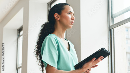 Confident Healthcare Worker Holding Digital Tablet Near a Bright Window in Modern Facility