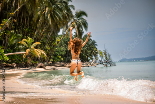 A young woman jumping on a seclude beach in the Caribbean Islands in Panama, Central America.