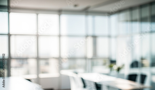 Blurred office interior with large windows and tables chairs creating a bright space.