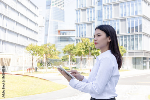 Foto A young Chinese professional woman using a tablet outside an office building