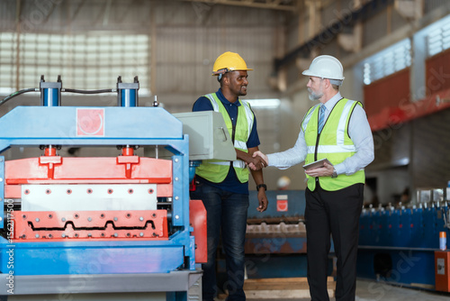 Workers collaborate at a manufacturing facility during business hours discussing equipment operation and safety practices