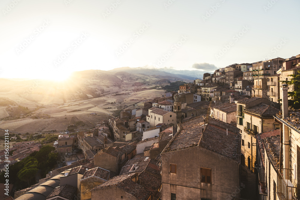 Obraz premium Terracotta rooftops overlooking rolling hills at sunset