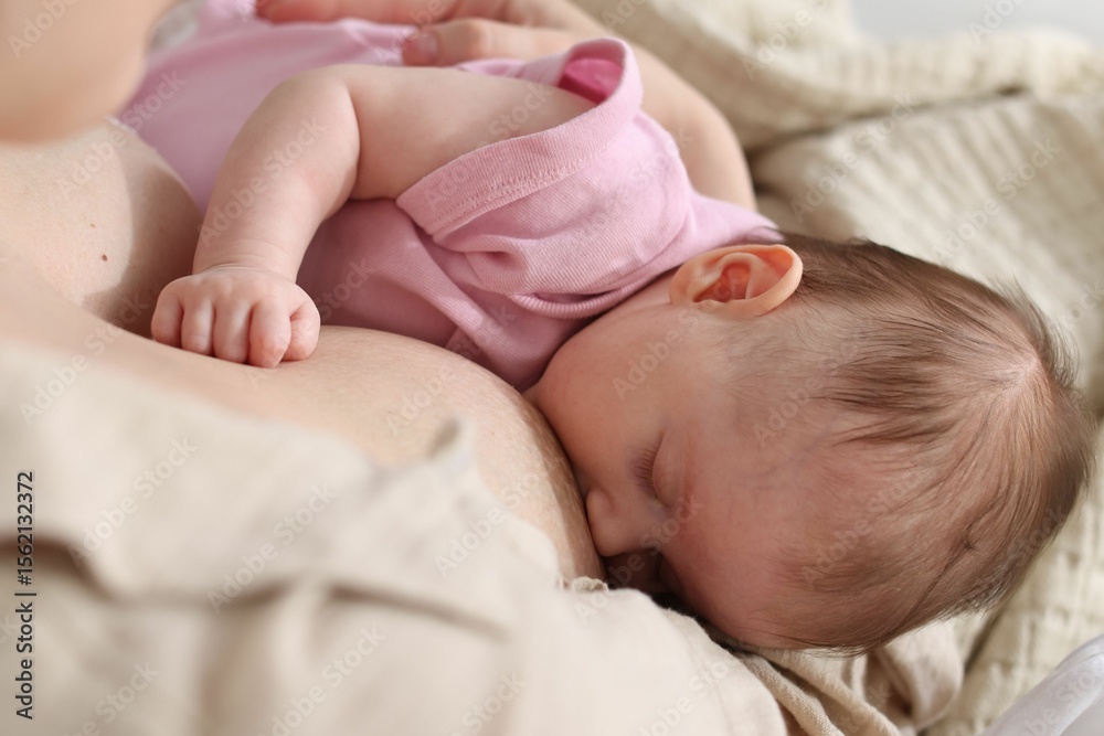 Mother breastfeeding her newborn baby indoors, above view Mother breastfeeding her newborn baby indoors, above view