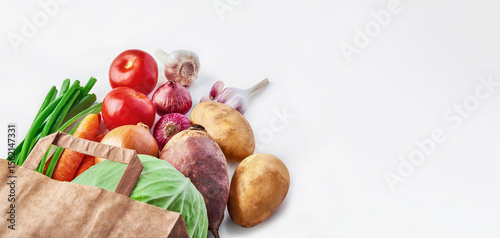 Vegetables in paper bag on white background. Food delivery, shopping, healthy eating, clean vegan vegetarian food concept. Copy space, banner, horizontal orientation