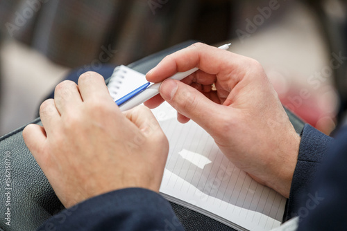 Male hands holding pen and notepad on a lecture, briefing, conference