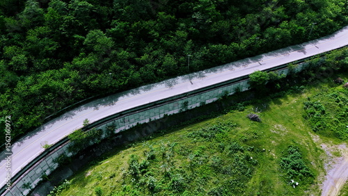 Aerial view of a road in the middle of the forest. Top view of asphalt road through forest with car adventure. Healthy environment road trip travel.