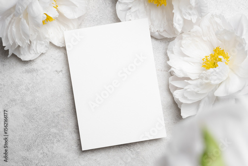 Blank invitation, flyer or greeting card mockup with copy space and peony flowers on stony background for wedding design projects