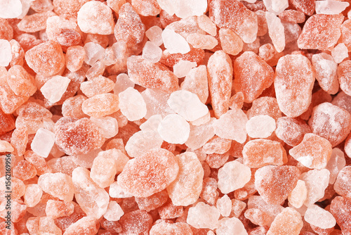 Himalayan pink salt crystals. Macro shot of coarse rock salt texture. Natural food seasoning background. Mineral nutrition source. Healthy culinary ingredient. Edible decorative pink grains surface.