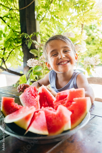 Smiling Child Eating Juicy Red Watermelon at Garden Table Surrounded by Greenery — Healthy Eating Concept for Kids