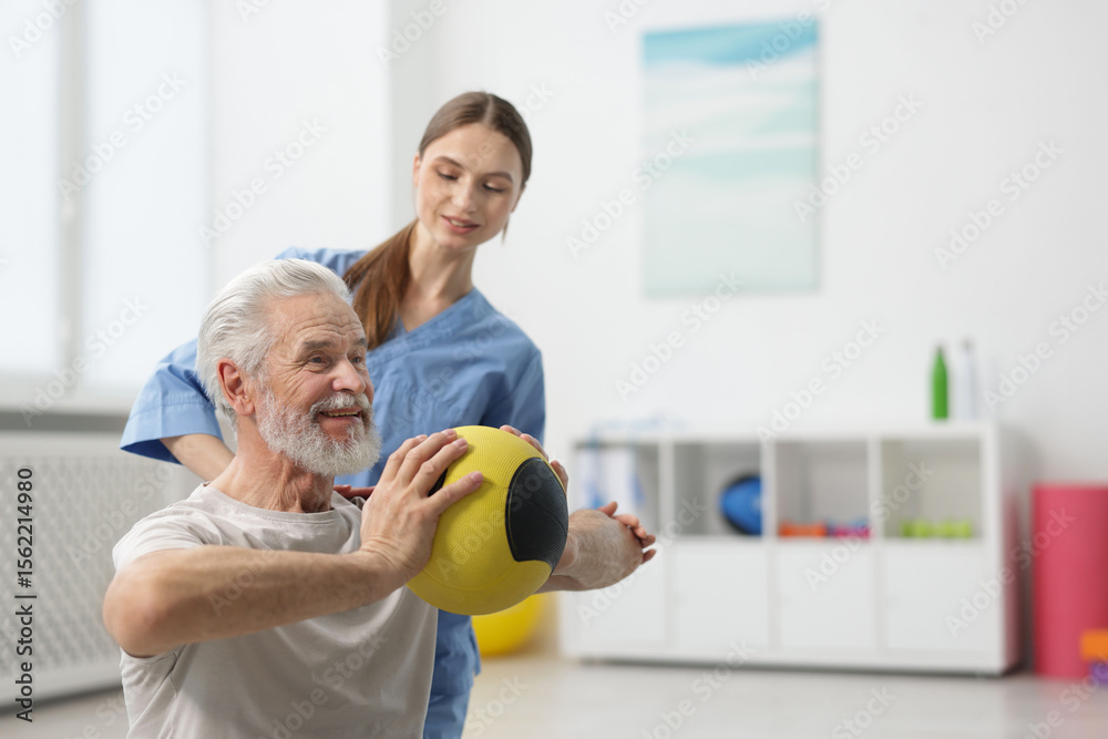 Fototapeta premium Doctor and patient exercising with medicine ball in clinic, space for text