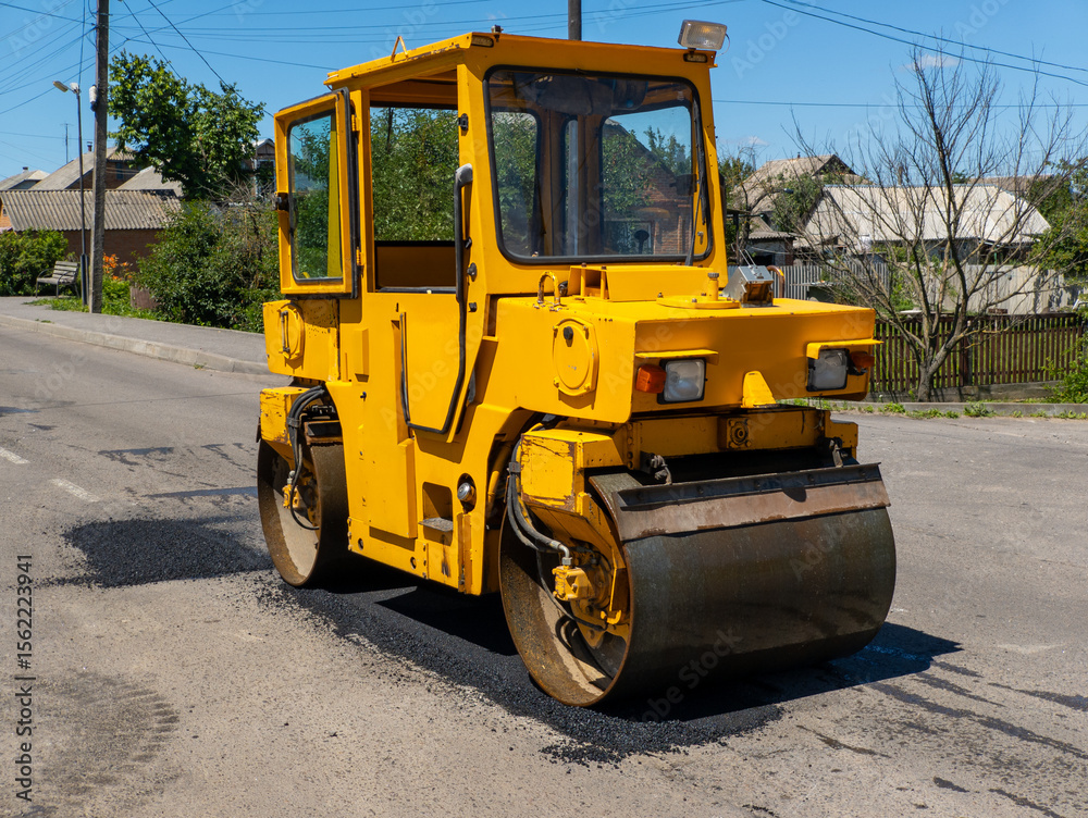 Fototapeta premium A large yellow road roller sitting on the side of a road