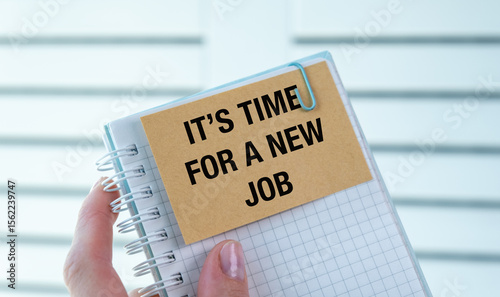 A person holding a notebook with a note that says It's Time For a New Job.