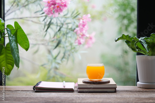 Orange juice cup and notebooks, indoor writing setting