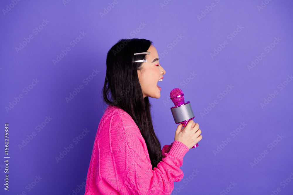 Young woman singing passionately with a vibrant microphone against a cheerful purple backdrop, exuding joy and style. Young woman singing passionately with a vibrant microphone against a cheerful purple backdrop, exuding joy and style.