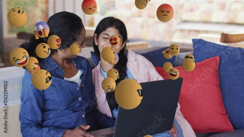 mother and daughter opening laptop in tech demo causing floating emojis around screen disappearing