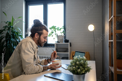 Freelancer eating breakfast and working from home office