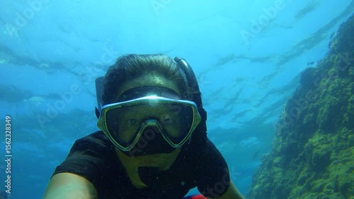 Wallpaper Mural duck diving down into sea blue ocean water from surface with snorkel in mouth and mask on face of an Asian female wearing black t shirt and bikini fin swimming down holding selfie camera next by coral Torontodigital.ca
