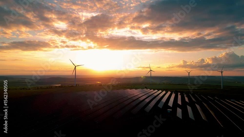 Solar panels park and wind turbines at sunset.Windmill turbines generating green energy electric.Green energy reduce carbon emissions and makes earth cleaner and more ecological.	
