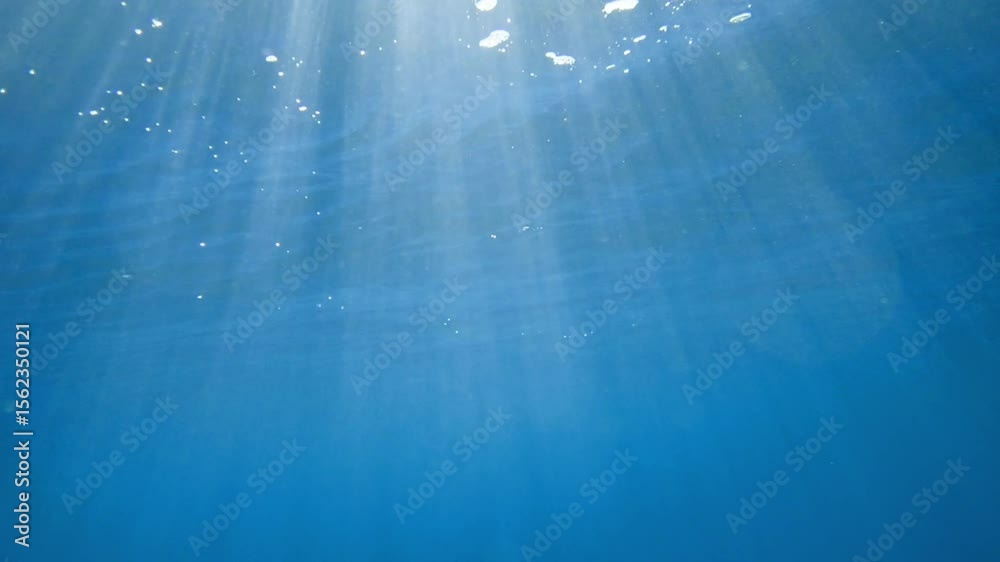 Sun ray and sun beam scenery underwater waves on surface of water slow motion ocean scenery for background, Clear blue ocean. Underwater shot of the smooth water surface, sun ray and sun beam scenery.