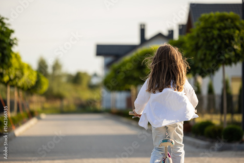 Photos Child enjoying bike ride on suburban trail with green scenery
