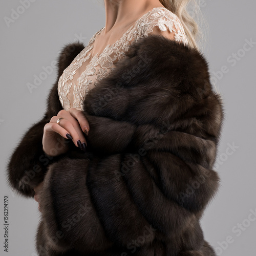 Elegant woman showcasing luxurious fur coat with intricate lace details