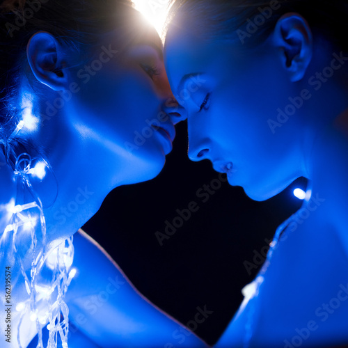 Two individuals share an intimate moment illuminated by blue lights