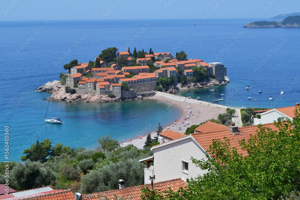 Obraz premium Breathtaking Panoramic View of Sveti Stefan Island in Montenegro, Showcasing its Historic Red-Roofed Buildings, Pristine Beaches, and Azure Adriatic Sea