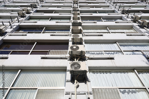 Neatly arranged air conditioning units on the wall of a vintage apartment building