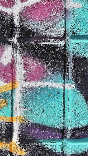 Colorful graffiti design painted on textured brick wall featuring vibrant turquoise and pink
