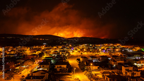 Fotografie Wildfire burning near Cesme, Turkey, threatening residential area at night
