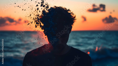 A young man stands on the edge of a vast ocean, his silhouette dark against the glowing hues of a fading sunset.