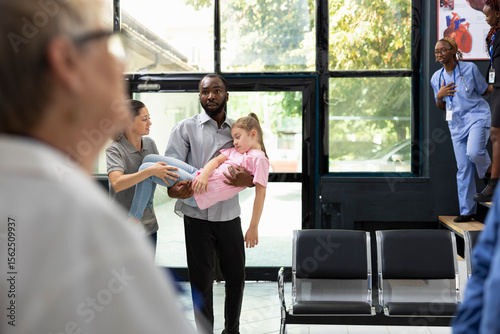 Fotografie Girl fainted and her african american father is carrying her in the hospital, waiting for immediate care response from the medical team