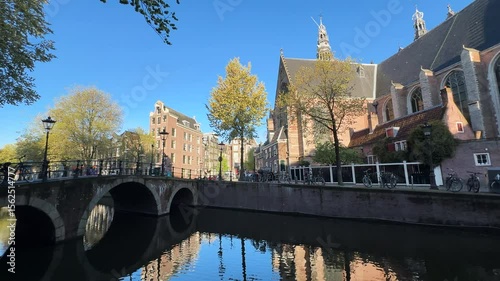 Facades of old historic Houses over canal water with Oude Kerk, Amsterdam, Netherlands