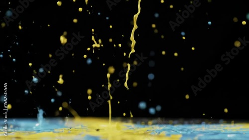 Splashes of yellow and blue liquid collide on a black background