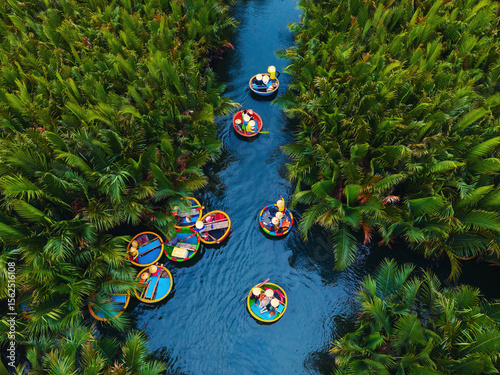 Fototapeta Aerial view of traditional coconut bamboo boats navigating lush greenery in hoi