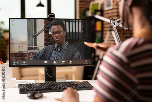 Male business advisor seen on computer screen, providing insights on strategy plans to black female entrepreneur during video call. African american individuals having virtual meeting on desktop pc.