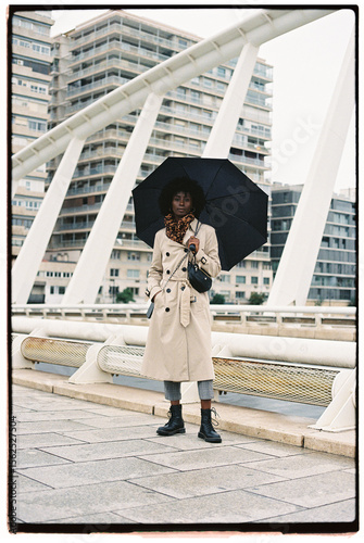 Woman standing on the bridge under umbrella
